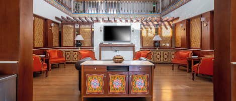A spacious lobby with a central island, wooden furniture, and a staircase with ornate railings.