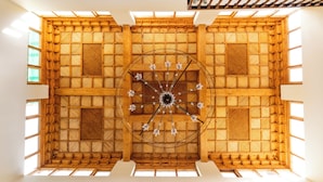 A high-ceilinged room with a wooden lattice ceiling and a central chandelier.
