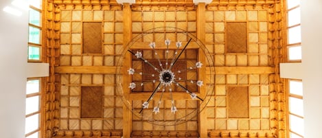 A high-ceilinged room with a wooden lattice ceiling and a central chandelier.