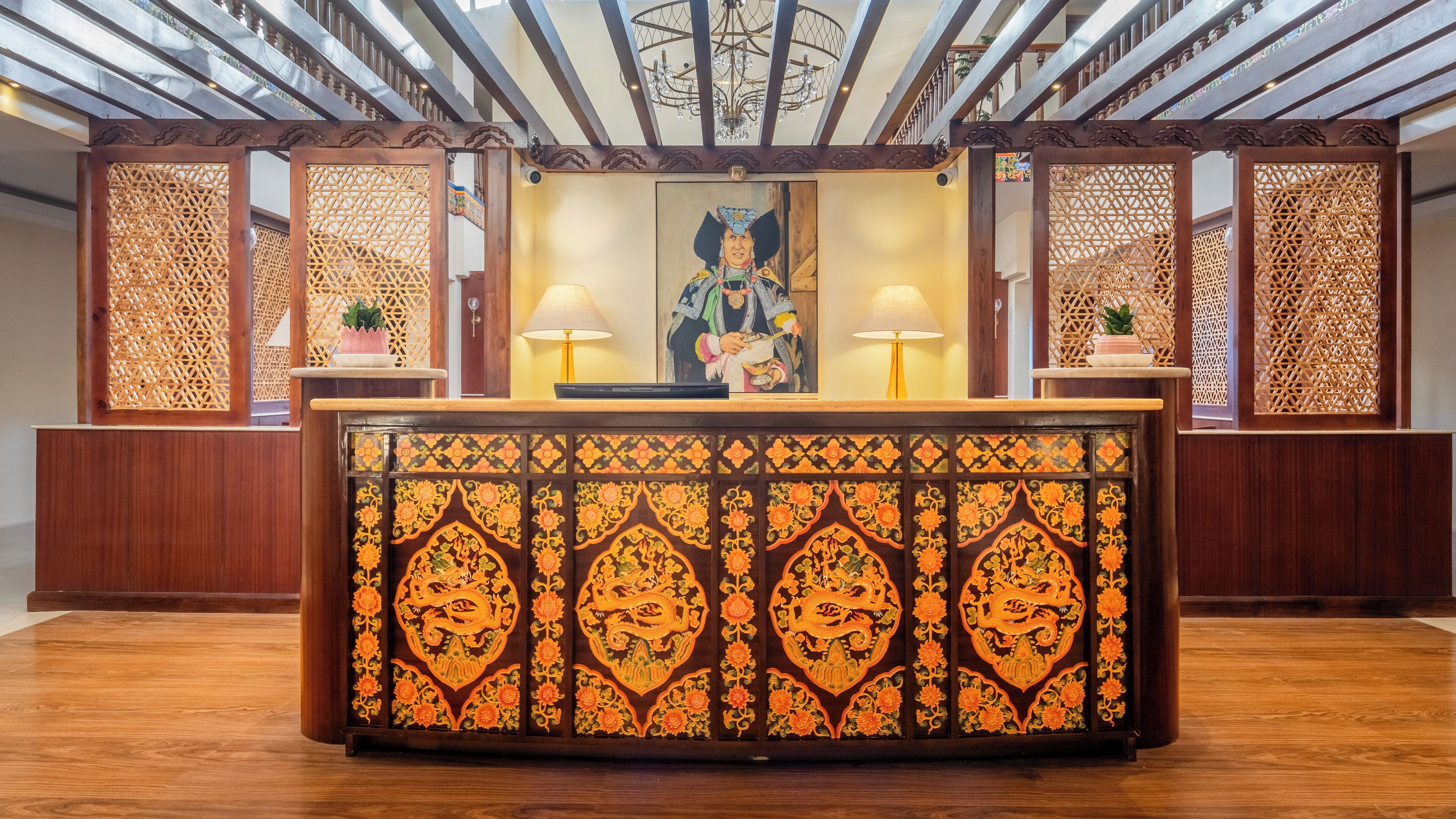 A reception desk with intricate woodwork and a chandelier.