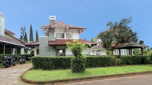 Ein zweistöckiges Haus mit Naturstein-Fassade, einem Ziegeldach und einem gepflegten Rasen.