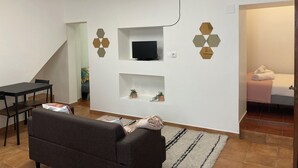 A modern living room with a sofa, a TV mounted on the wall, and a dining area with a table and chairs. - Cozy Apartment , Casa Para um fim de Semana Para Descobrir a Vila de Elvas (Ajuda, Salvador e Santo Ildefonso)