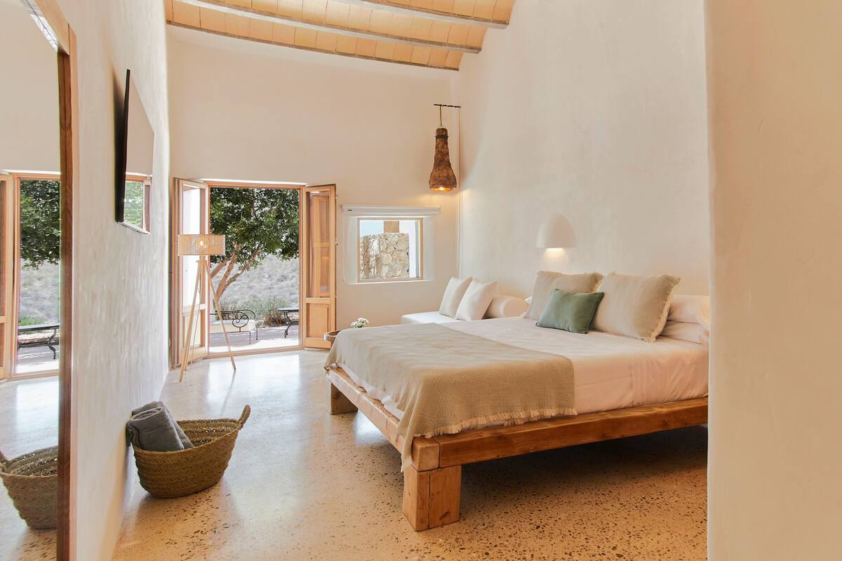 Quarto espaçoso com uma cama grande, piso de madeira e vista para o exterior.