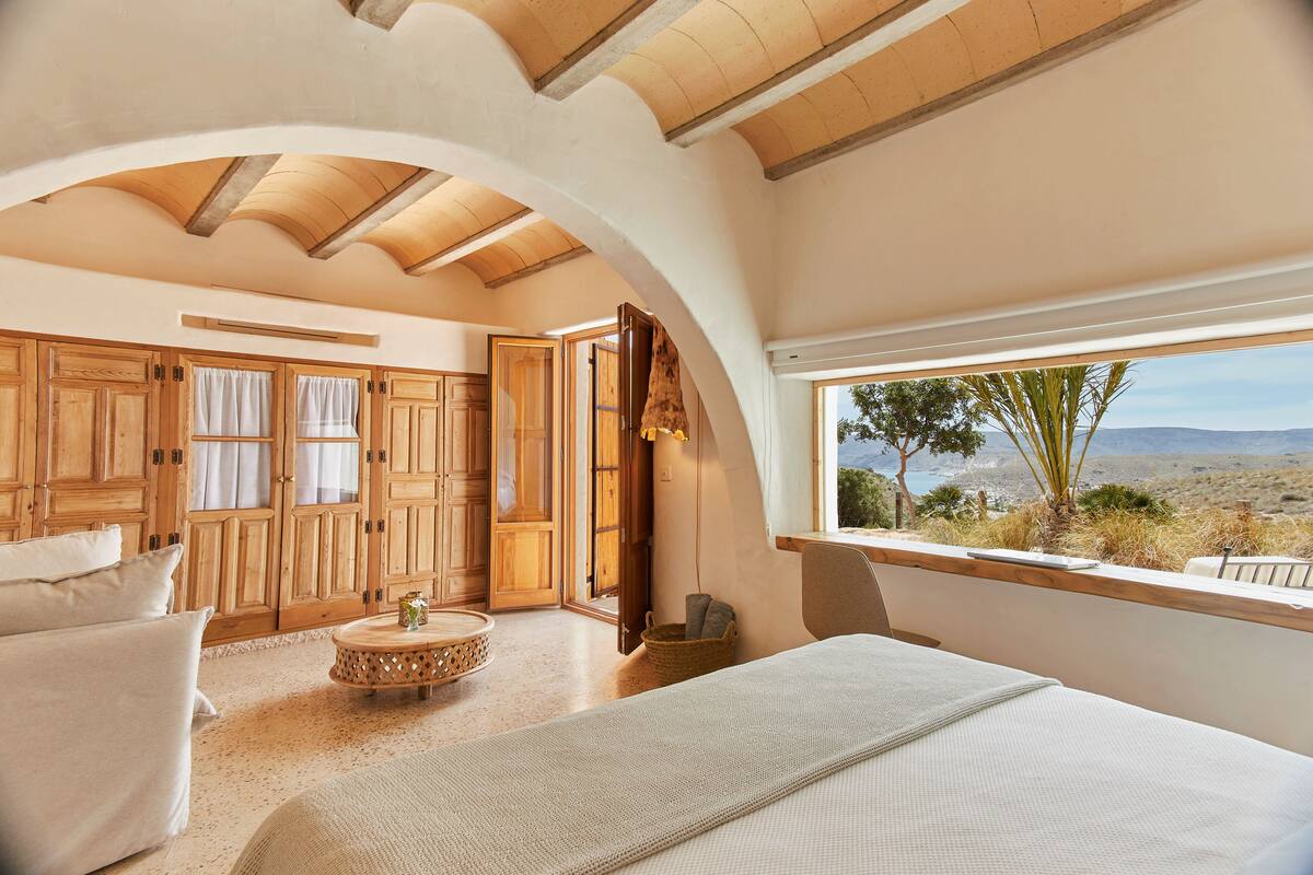 Quarto espaçoso com cama grande, guarda-roupa de madeira e vista para a paisagem.