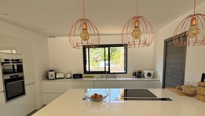 A modern kitchen with a central island, bar stools, and pendant lighting.