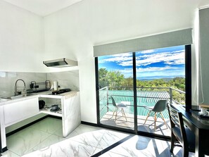 Eine moderne Küche mit einem großen Fenster und Blick auf einen Balkon mit Sitzgelegenheiten.