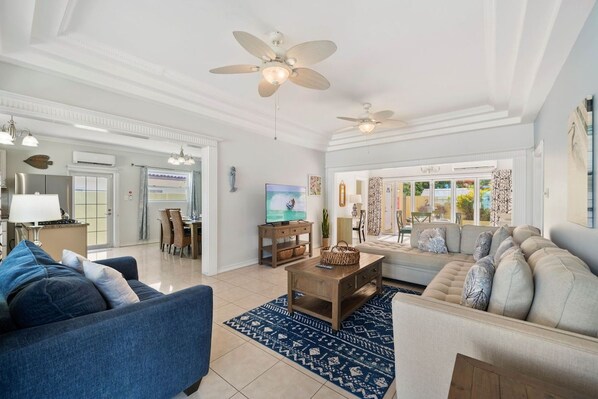 A spacious living room with a blue sofa, a beige sofa, a coffee table, and a ceiling fan.