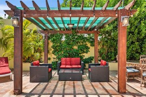 A covered outdoor seating area with wicker furniture and a pergola. - 3BR Home w/ Private Pool & BBQ near Palm Beach (Noord)