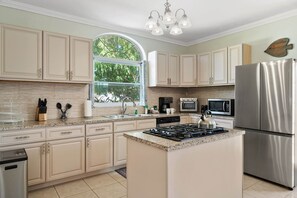 A modern kitchen with a central island, stainless steel appliances, and light-colored cabinetry.