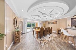 Un comedor con una mesa y sillas de madera, un ventilador de techo y vistas al exterior.