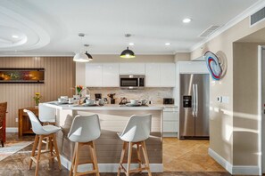 A modern kitchen with a central island, stainless steel appliances, and pendant lighting. - Ground-level 4BR Lake View Condo, Walk to Beach (Noord)