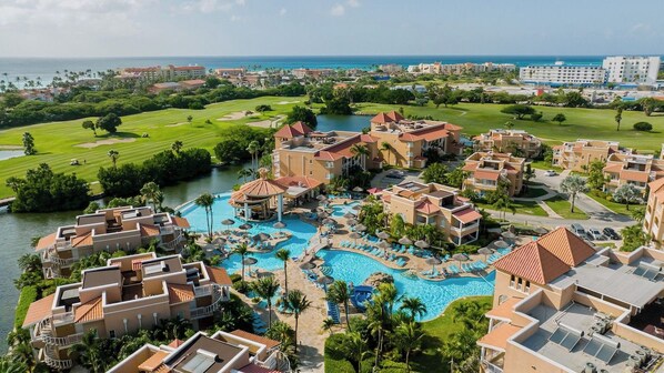 Un complejo turístico con varias piscinas, un campo de golf y vistas a la playa.