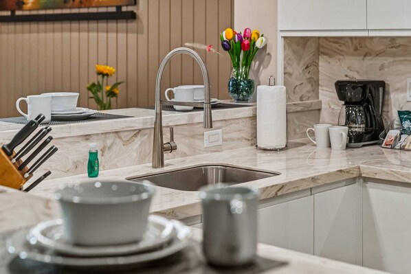 A modern kitchen with a sink, countertop, and a coffee maker.