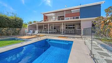 A modern two-story house with a swimming pool, outdoor seating, and a covered patio.