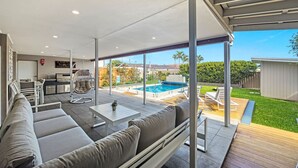 Un espacio exterior moderno con piscina, un porche cubierto y zona de cocina.