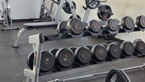 A gym with weightlifting equipment, including dumbbells and barbells, and a bicycle. - Lux Suites Gatundu Heights Kileleshwa (Nairobi)