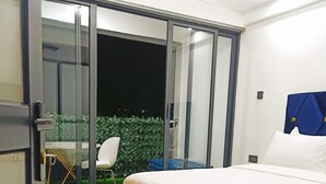 A bedroom with a bed, a sliding glass door to a balcony, and a small table with chairs. - Lux Suites Gatundu Heights Kileleshwa (Nairobi)