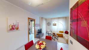 Un salon moderne comprenant un canapé, une table à manger avec des chaises, un téléviseur et un grand tableau abstrait.