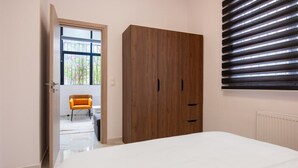 Un dormitorio con una cama grande, un armario y una ventana con persianas.