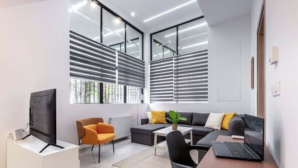 Una sala de estar moderna con un sofá, sillones, una mesa de centro, un televisor y una computadora portátil.