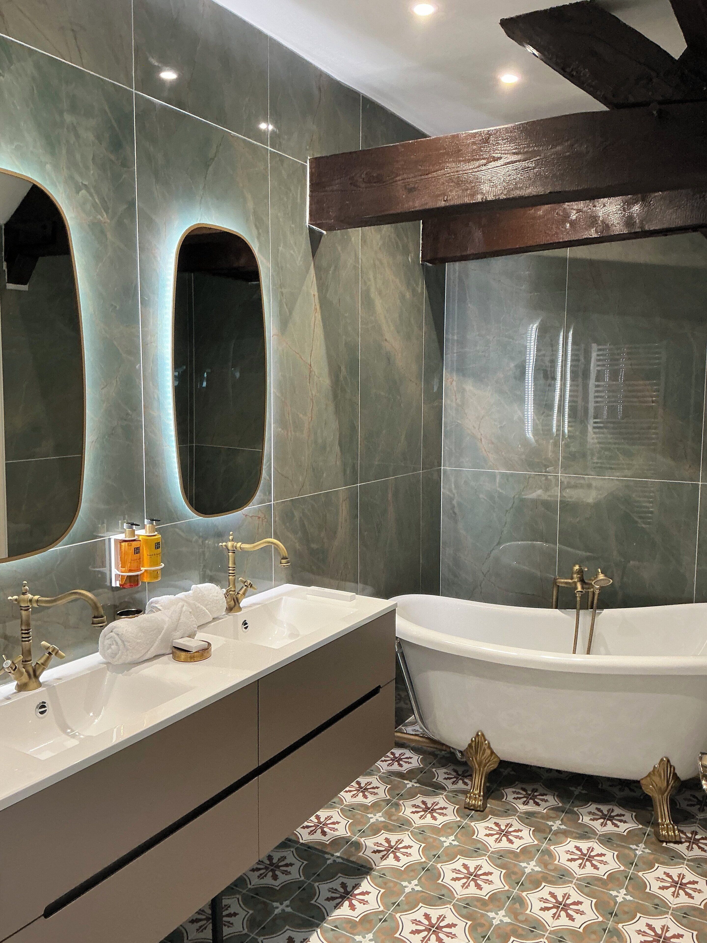A bathroom with a freestanding bathtub, a double sink vanity, and two large mirrors.