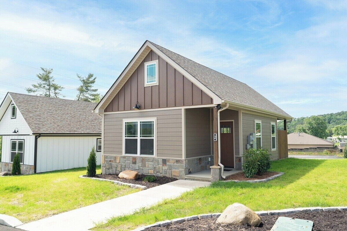 A single-story house with a brown siding exterior, a stone foundation, and a front porch.