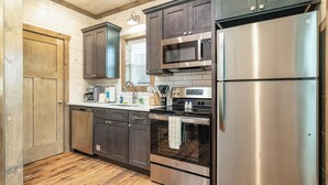 A modern kitchen with dark wooden cabinets, stainless steel appliances, and a wooden floor. - 5 Minutes From Dollywood/In DwTn Pigeon Forge (Pigeon Forge)