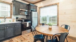 A modern kitchen with dark cabinets, stainless steel appliances, and a wooden dining table with chairs. - 5 Minutes From Dollywood/In DwTn Pigeon Forge (Pigeon Forge)