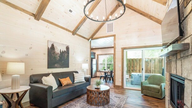 A cozy living room with a fireplace, a dark sofa, a round coffee table, and a large painting on the wall.