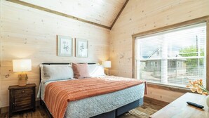 A bedroom with a bed, bedside tables, a window, and framed pictures on the wall.