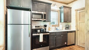 A modern kitchen with stainless steel appliances, dark wooden cabinets, and a wooden floor. - 5 Minutes From Dollywood/In DwTn Pigeon Forge (Pigeon Forge)