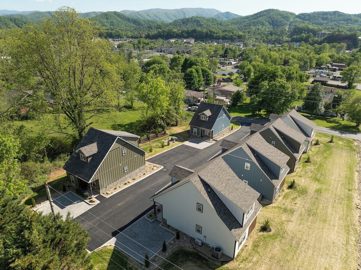 Un quartier résidentiel comprenant plusieurs maisons, une grande grange et une allée pavée.