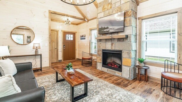 A cozy living room with a stone fireplace, a comfortable sofa, a coffee table, and a television mounted on the wall. - 5 Minutes From Dollywood/In DwTn Pigeon Forge (Pigeon Forge)