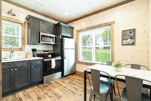 Enjoy cooking in this well-equipped kitchen with a microwave, oven, and refrigerator, adjacent to a dining area with a table and chairs.