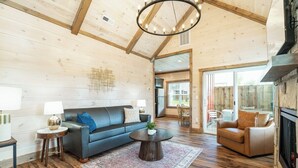 Un salón amplio con techo de madera, chimenea y un ventanal grande.