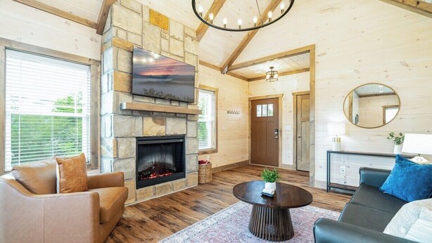 Una sala de estar acogedora con chimenea de piedra, sofás de cuero, una mesa de centro redonda y un espejo grande.