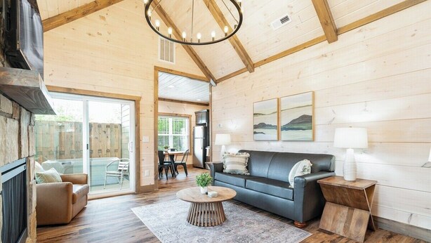 A spacious living room with a wooden ceiling, a sofa, a coffee table, and a fireplace.