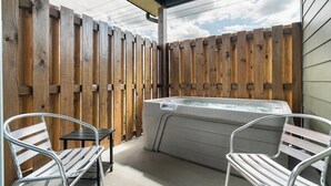 A hot tub area with wooden fencing, two metal chairs, and a small table.