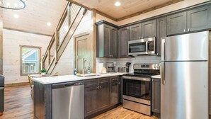 A modern kitchen with stainless steel appliances, dark cabinets, and a wooden floor. - 5 Minutes From Dollywood/In DwTn Pigeon Forge (Pigeon Forge)