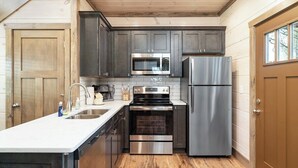 A compact kitchen with dark cabinets, stainless steel appliances, and a wooden floor. - 5 Minutes From Dollywood/In DwTn Pigeon Forge (Pigeon Forge)