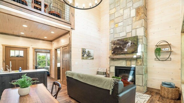 A spacious living area with a fireplace, wooden flooring, and a high ceiling. - 5 Minutes From Dollywood/In DwTn Pigeon Forge (Pigeon Forge)