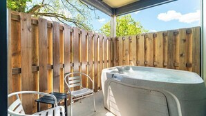 A hot tub under a covered patio with a wooden fence and metal chairs. - 5 Minutes From Dollywood/In DwTn Pigeon Forge (Pigeon Forge)