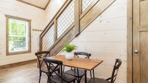 Ein Essbereich mit einem Holztisch, vier Stühlen, einer Topfpflanze und einem Fenster mit Jalousien.