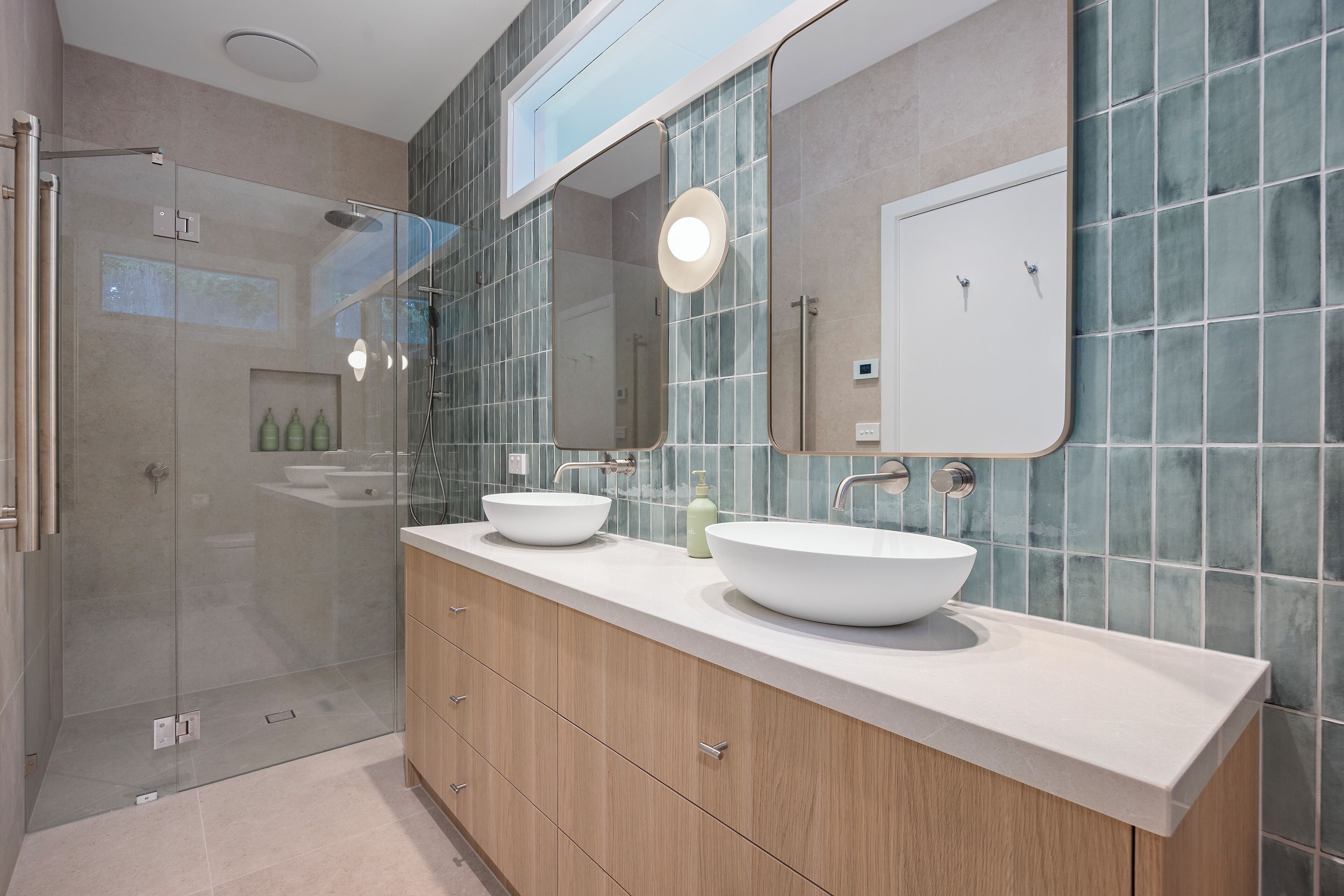 A modern bathroom with a glass-enclosed shower, two sinks, and a large mirror.