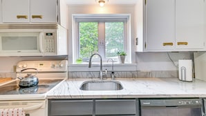 A kitchen with a built-in microwave, stove, sink, and dishwasher. There is a window with a view of trees outside. - Family Home w/ Yard & Fire Pit in Middleburgh! (Middleburgh)
