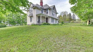 A two-story house with a front porch, surrounded by a grassy yard and trees. - Family Home w/ Yard & Fire Pit in Middleburgh! (Middleburgh)