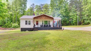 A small, single-story cabin with a porch, surrounded by a grassy yard and dense forest. - 3 Mi to Dtwn! Forest City Haven w/ Furnished Patio (Forest City)
