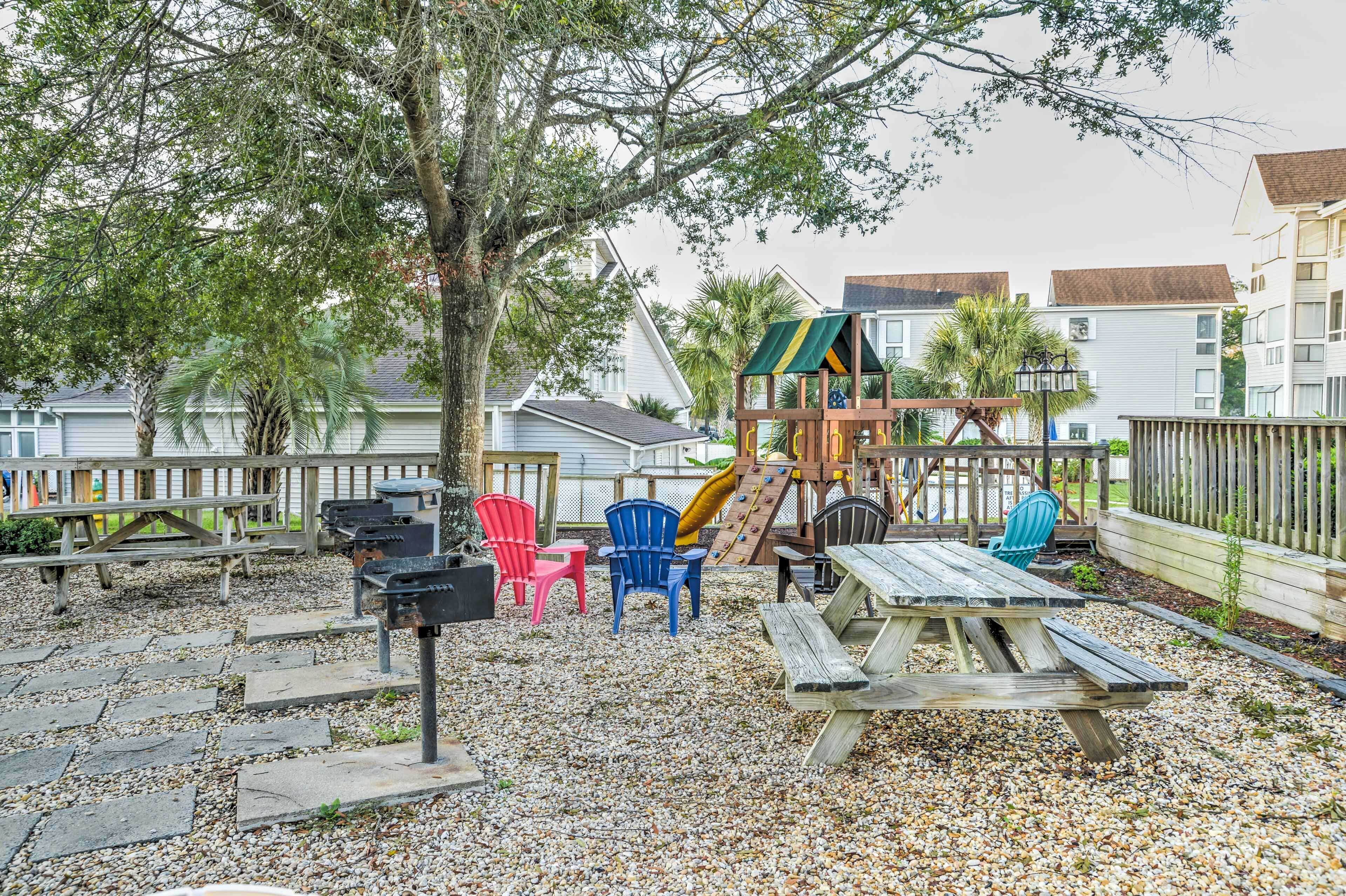 A playground with a slide, climbing wall, and picnic table with chairs.