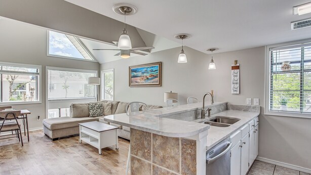 A modern kitchen with a central island, a dining area with a sofa and table, and large windows providing natural light. - 1 Block to Beach: Myrtle Beach Condo w/ Pool! (Myrtle Beach)