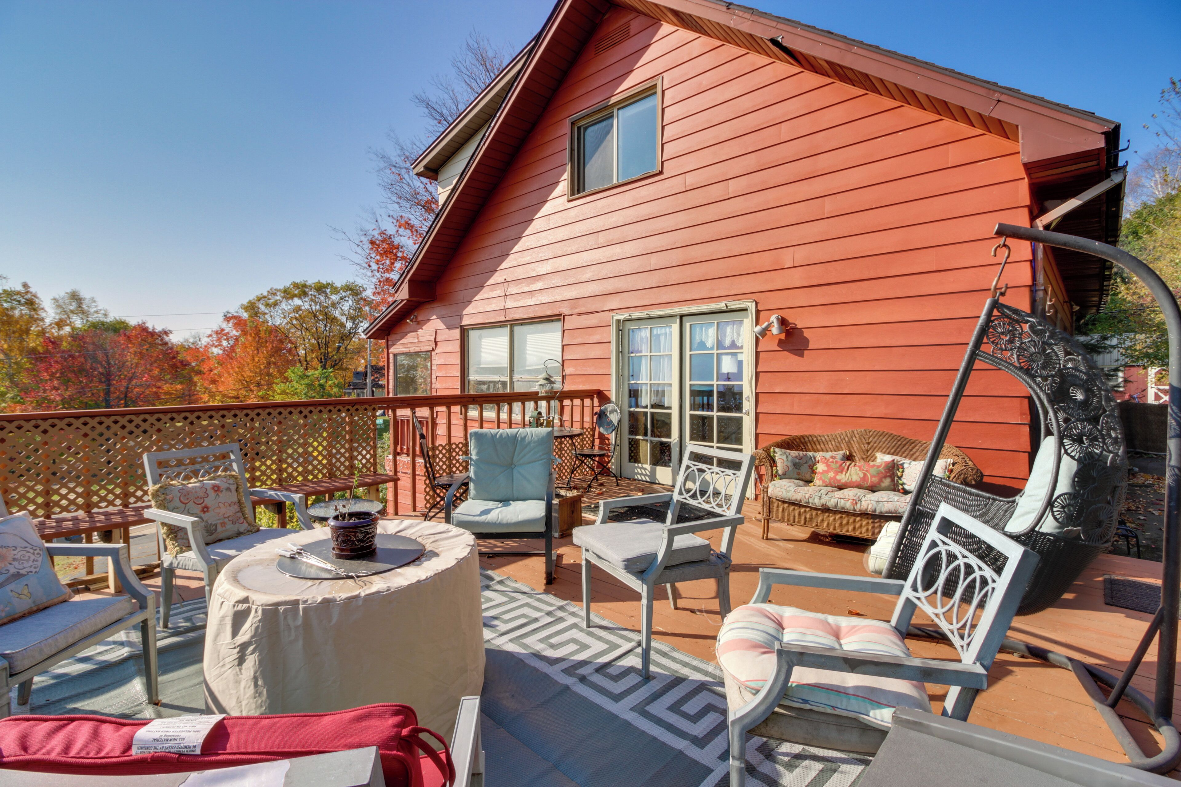 A red wooden house with a patio area featuring outdoor furniture and a swing chair.